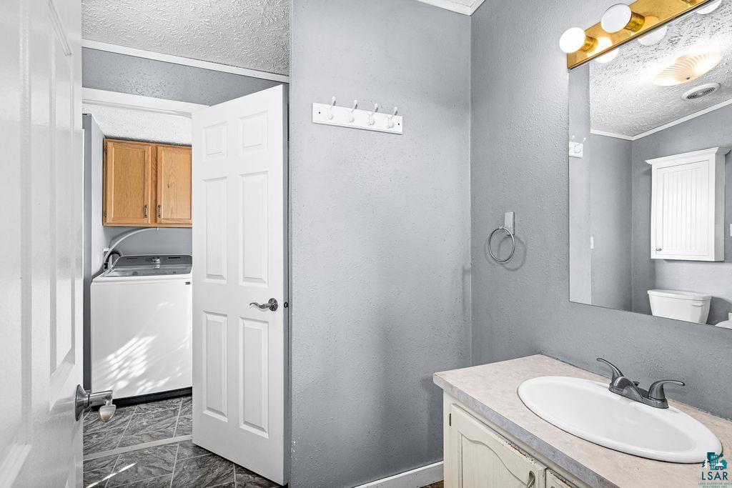 6638 Tabako Road Wright, MN 55798 - Photo 18 of 34 Bathroom with a textured ceiling, a textured wall, washer / dryer, and vanity
