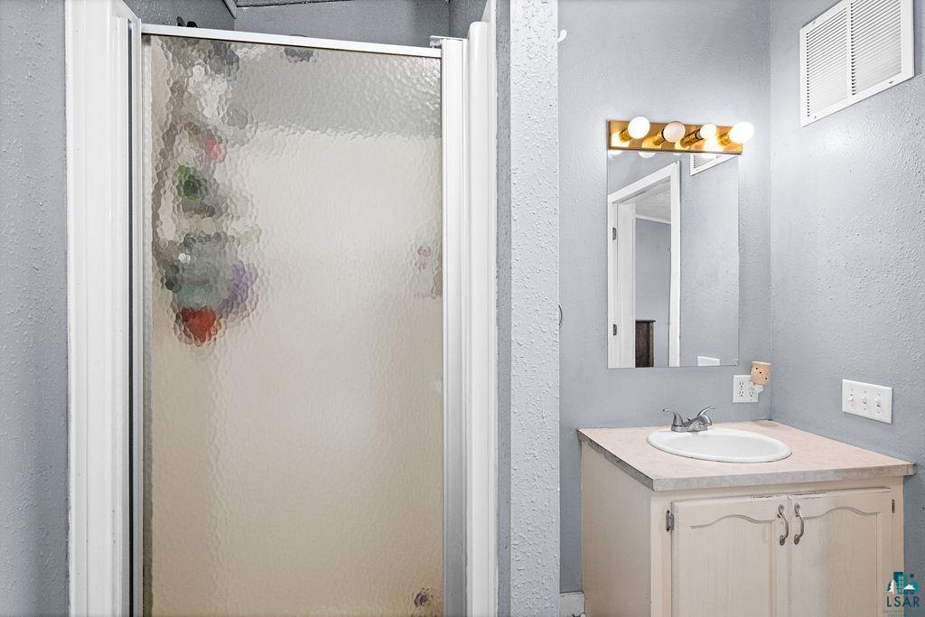 6638 Tabako Road Wright, MN 55798 - Photo 19 of 34 Bathroom featuring a textured wall, vanity, and a shower stall