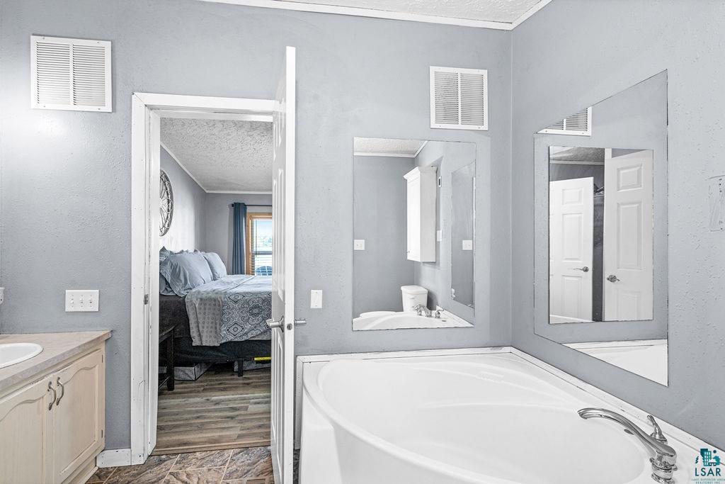 6638 Tabako Road Wright, MN 55798 - Photo 20 of 34 Full bath featuring vanity, a textured ceiling, connected bathroom, a garden tub, and a textured wall