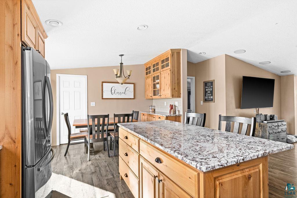 6638 Tabako Road Wright, MN 55798 - Photo 9 of 34 Kitchen with light wood finish cabinetry, freestanding refrigerator, light stone countertops, a center island, and lofted ceiling