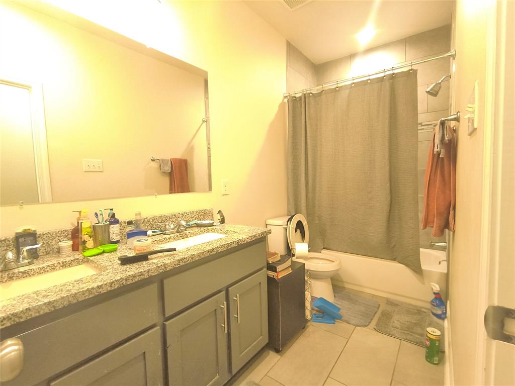 3027 Ames Road Lancaster, TX 75134 - Photo 29 of 35 Bathroom featuring a dual-sink vanity with a granite-style countertop, gray cabinetry, a tub/shower combination with subway tile surround, and light-toned floor tile