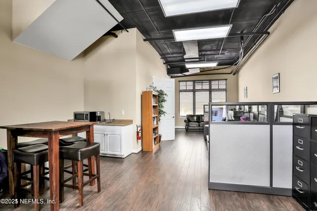 a living room with a dining table wooden floor and a window