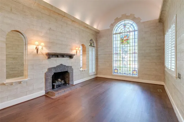 an empty room with wooden floor fireplace and windows
