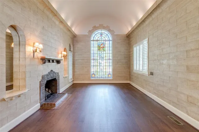 a view of an empty room with wooden floor fireplace and a window