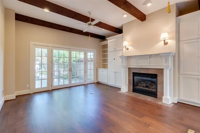 a view of an empty room with wooden floor fireplace and a window