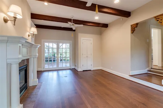 a view of an empty room with wooden floor and a fireplace