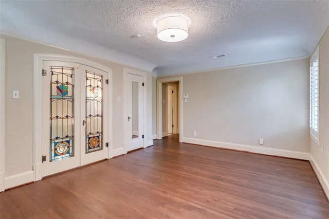 a view of an empty room with window and wooden floor