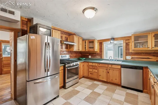a kitchen with stainless steel appliances granite countertop a refrigerator a stove and a sink