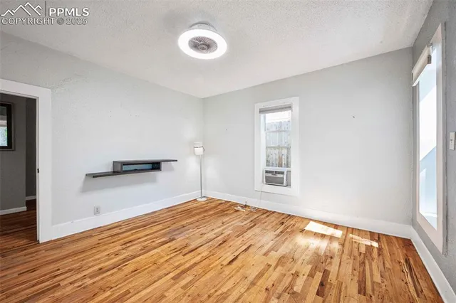 a view of an empty room with wooden floor and a window