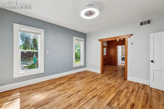 an empty room with wooden floor and windows