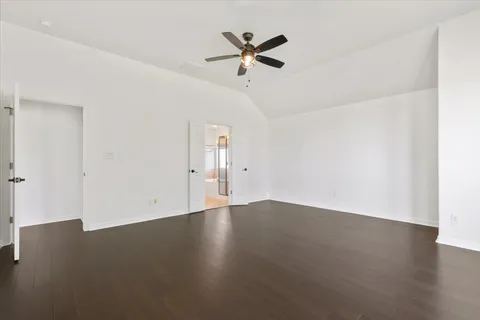 an empty room with wooden floor and ceiling fan