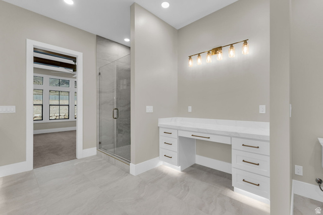 2828 Jojo Road Eagle Mountain, UT 84005 - Photo 29 of 63 Spacious bathroom featuring a built-in vanity with a light-colored countertop, white cabinetry with dark hardware, and a multi-bulb light fixture