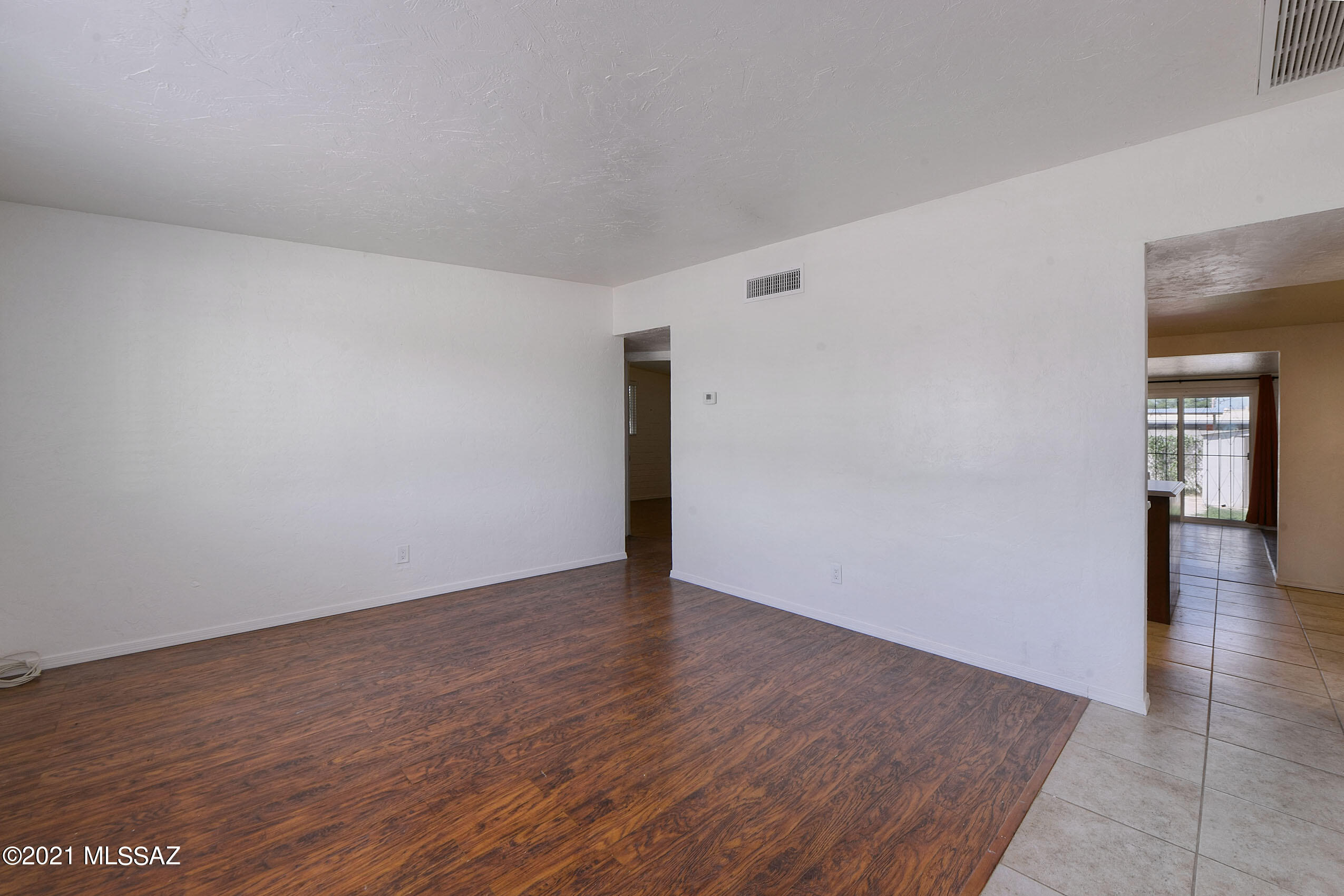 1470 West Roger Road Tucson, AZ 85705 - Photo 3 of 18 a view of an empty room with wooden floor and a window