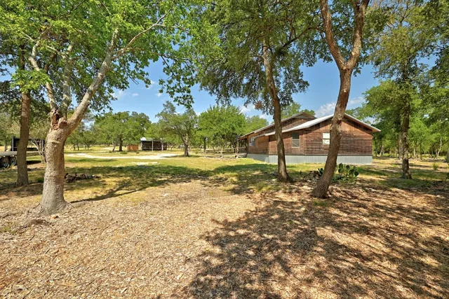 a view of a house with backyard and trees