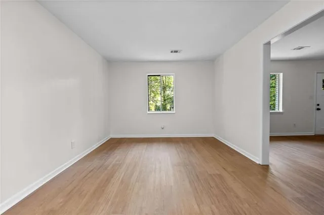 an empty room with wooden floor and window