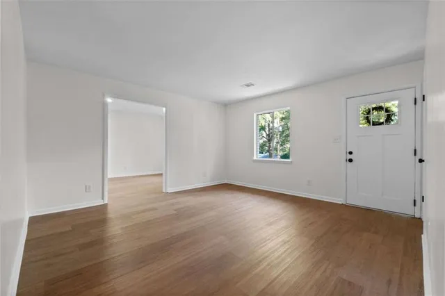 an empty room with wooden floor and windows