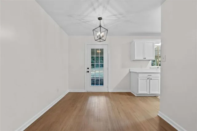 an empty room with wooden floor cabinet and windows