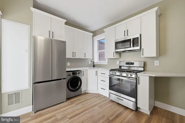 a kitchen with stainless steel appliances a white stove a microwave and a refrigerator