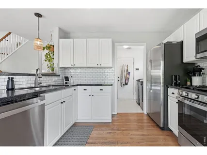 a kitchen with stainless steel appliances granite countertop a refrigerator a sink a stove and white cabinets