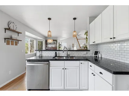 a kitchen with granite countertop a sink a white cabinets and a wooden floor