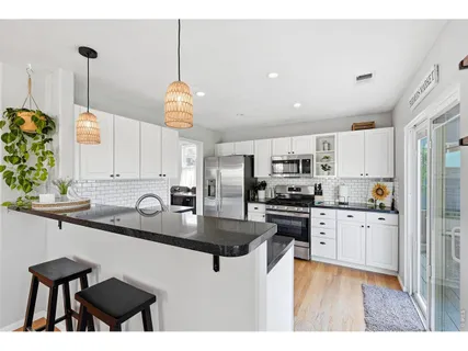 a kitchen with stainless steel appliances granite countertop a sink a stove and a wooden floors