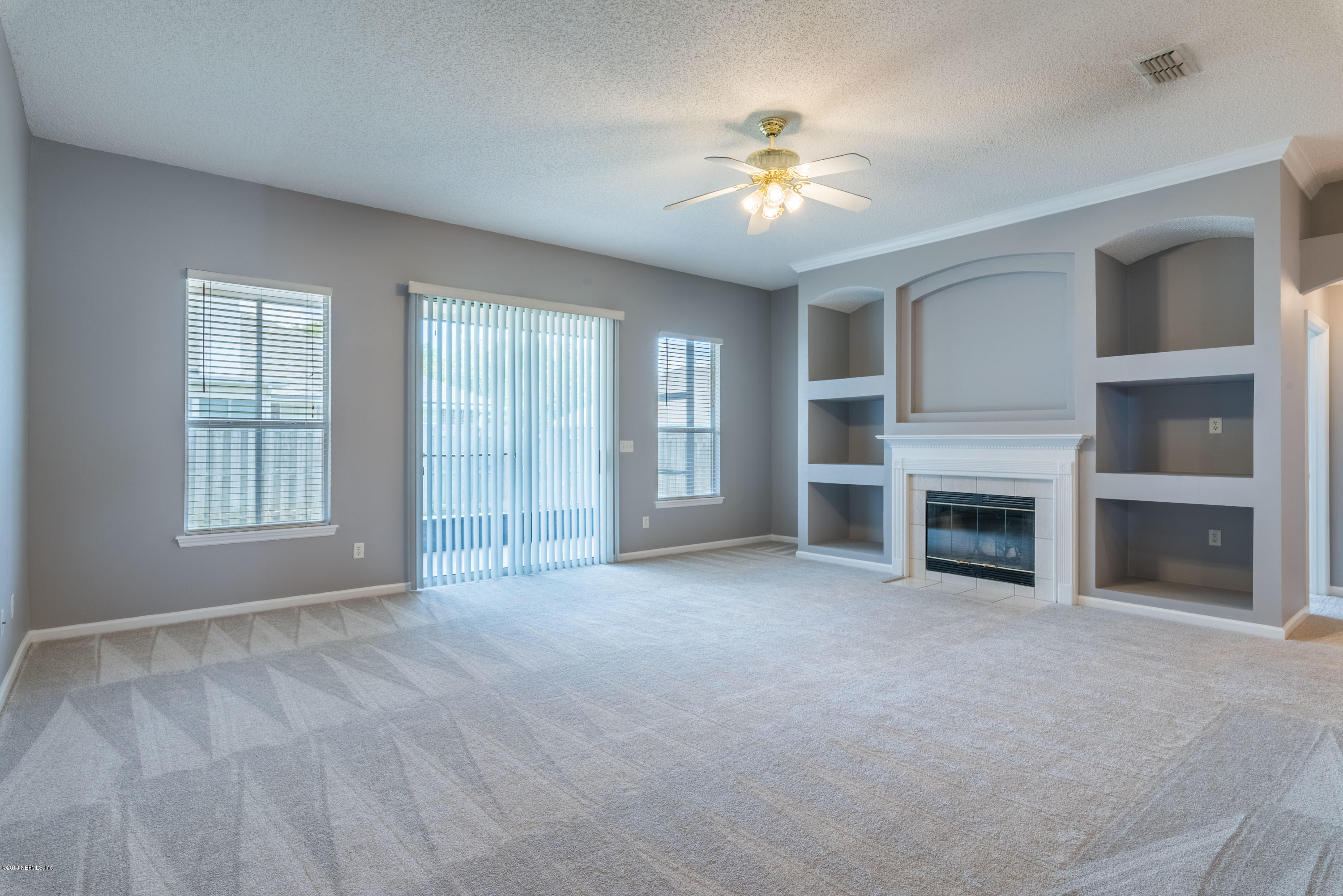 10368 Sugar Grove Road Jacksonville, FL 32221 - Photo 11 of 28 an empty room with windows and chandelier fan
