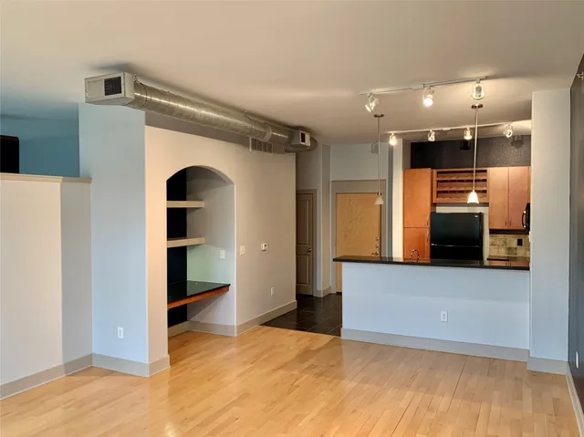 a view of an empty room with kitchen and a window