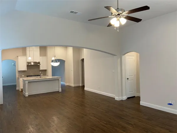 a large white kitchen with a large window stainless steel appliances and chandelier