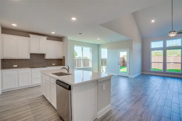 a large kitchen with granite countertop a large counter top a sink stainless steel appliances and cabinets