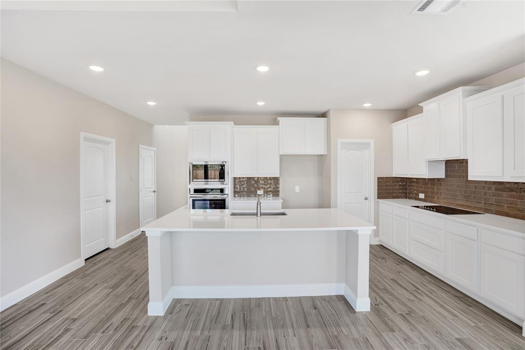 8526 Royal Star Road Rowlett, TX 75089 - Photo 6 of 21 a large white kitchen with wooden floors and stainless steel appliances