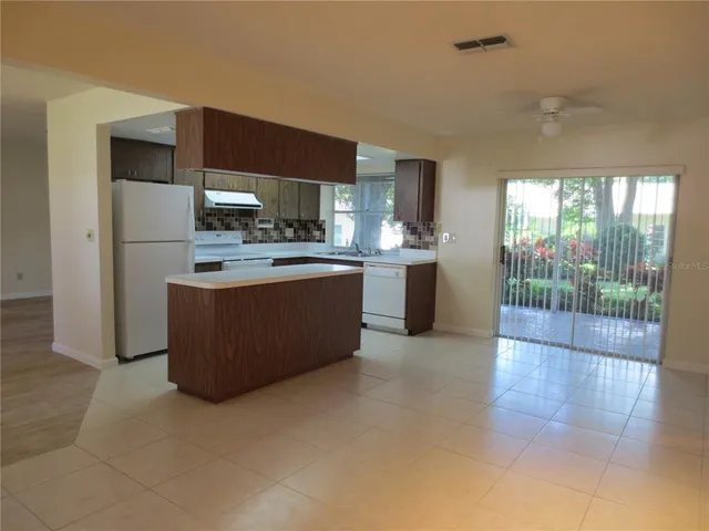 a large kitchen with stainless steel appliances granite countertop a stove top oven a sink dishwasher a refrigerator and cabinets