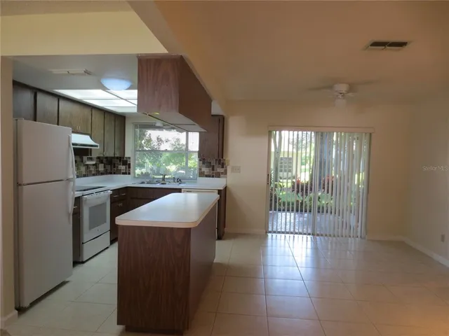 a kitchen with granite countertop a refrigerator a sink a stove top oven and cabinets