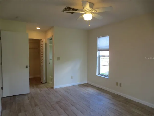 a view of empty room with wooden floor and fan