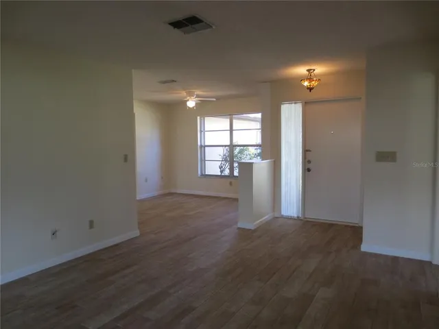 an empty room with wooden floor and windows