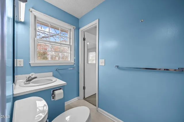 a bathroom with a toilet a sink a window and mirror