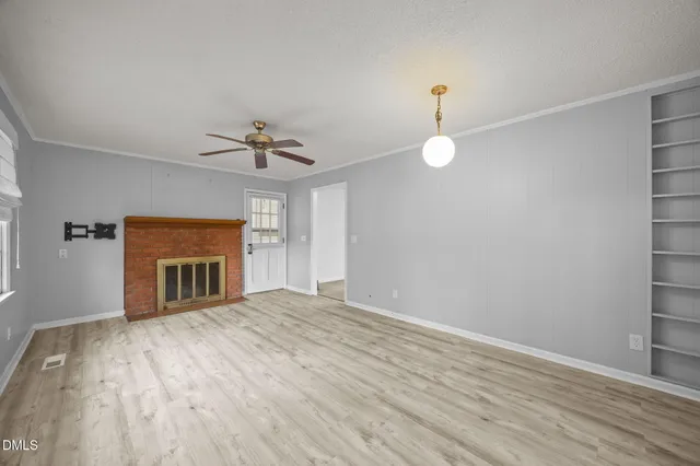 a view of an empty room with a fireplace and a window