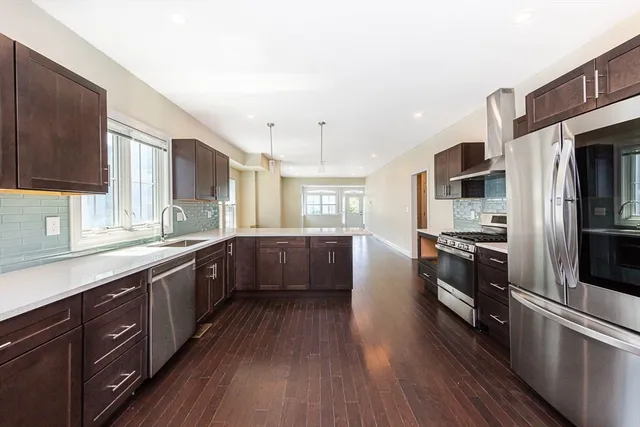 a kitchen with stainless steel appliances a sink cabinets and wooden floor