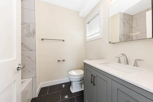 a bathroom with a granite countertop sink a toilet and a mirror