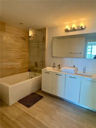 a bathroom with a tub sink and mirror