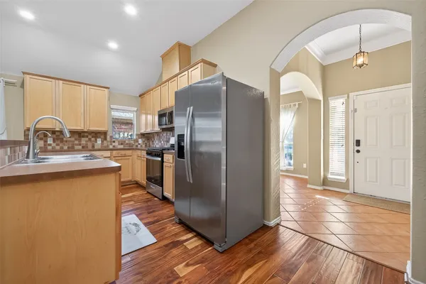 a kitchen with stainless steel appliances granite countertop a refrigerator a sink a stove and a wooden floors