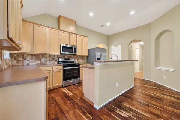 a kitchen with stainless steel appliances granite countertop a refrigerator a stove and a sink