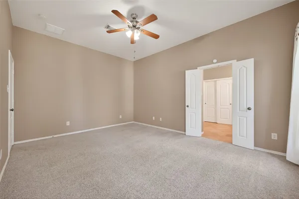 an empty room with closet and a ceiling fan