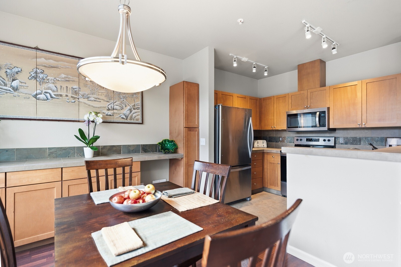 23420 Southeast Black Nugget Road, Unit F302 Issaquah, WA 98029 - Photo 7 of 19 a kitchen with stainless steel appliances granite countertop a stove refrigerator a dining table and chairs with wooden floor