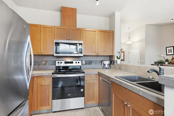 a kitchen with stainless steel appliances a stove a sink a microwave a refrigerator and cabinets