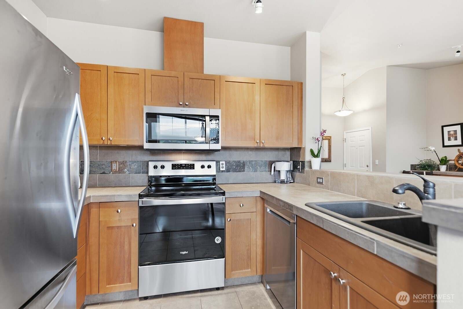 23420 Southeast Black Nugget Road, Unit F302 Issaquah, WA 98029 - Photo 9 of 19 a kitchen with stainless steel appliances a stove a sink a microwave a refrigerator and cabinets