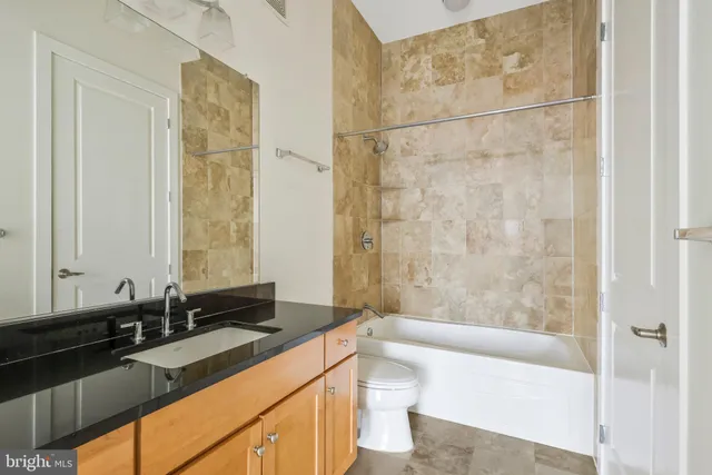 a bathroom with a granite countertop sink a toilet and shower