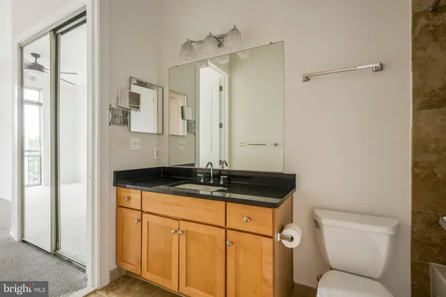 a bathroom with a granite countertop sink a toilet a mirror and shower