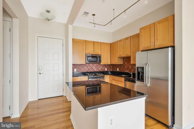 a kitchen with granite countertop a refrigerator a sink a stove and cabinets