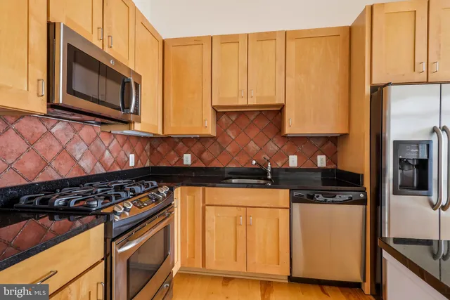 a kitchen with stainless steel appliances granite countertop a stove a sink and a microwave