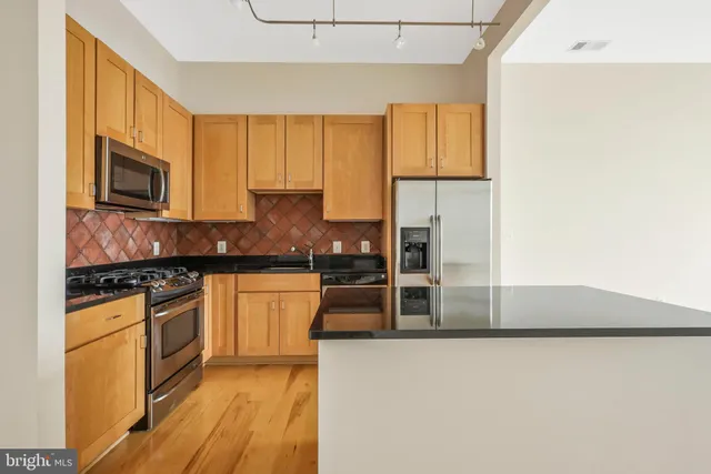 a kitchen with stainless steel appliances granite countertop a stove a sink and a refrigerator
